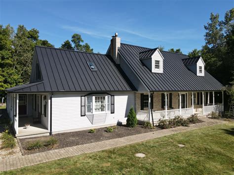 vlack metal roof with white house|house with black metal roof.